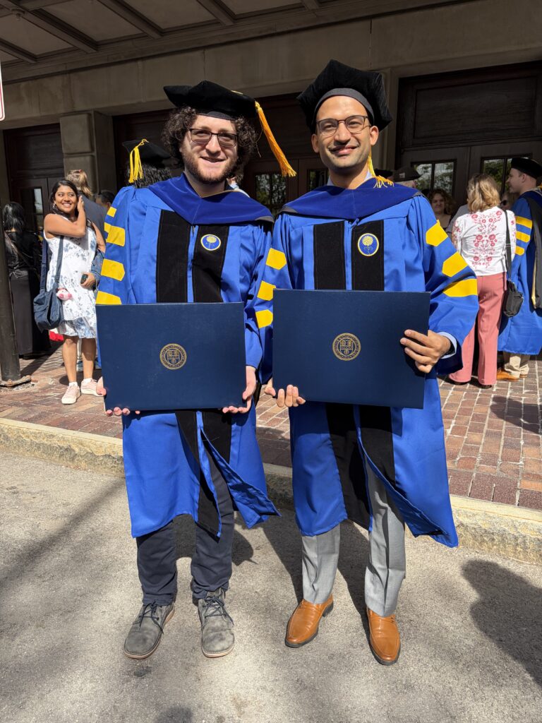 two individuals wearing doctoral regalia