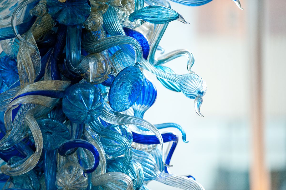 A large blue glass sculpture suspended from the ceiling in a well-lit room, showcasing intricate design and color.