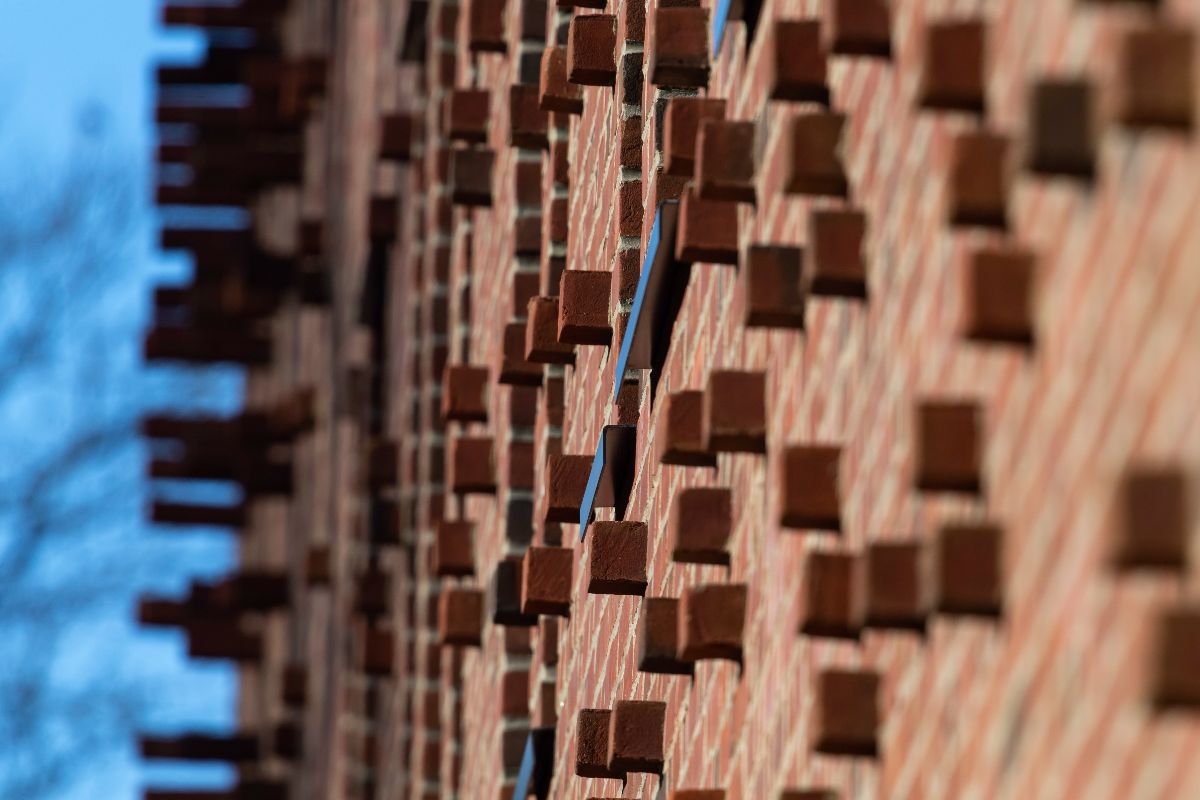 Close-up of a textured brick wall featuring numerous square patterns in a warm, earthy tone.